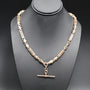 Gold chain necklace on a black mannequin bust against a dark background